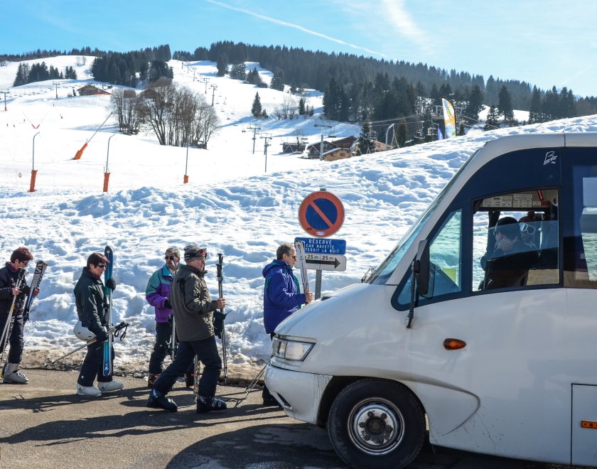 Des skieurs en train de monter dans une navette au pied des pistes 